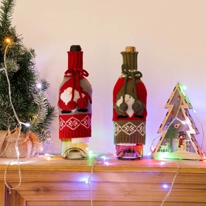 Detailed view of knitted Christmas wine bottle covers with pompoms in a festive home setting