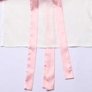 Detailaufnahme von glattem weißem Seidenstoff mit hängenden rosa Bändern am Saum