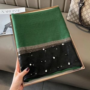 Detail of green and black pleated silk scarf with pearl beads in a gold gift box