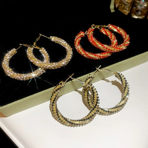 Detailed view of large twisted round earrings with red, white, and black rhinestones
