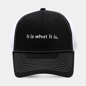 Detailed view of embroidery 'it is what it is' on a mesh panel trucker baseball cap