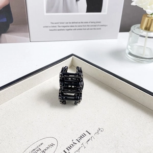 Detail shot of a black floral rhinestone hair claw clip on a white canvas display box