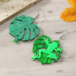Detailansicht der Monstera-Blatt und Frosch Ohrringe aus Acryl auf hellem Stein