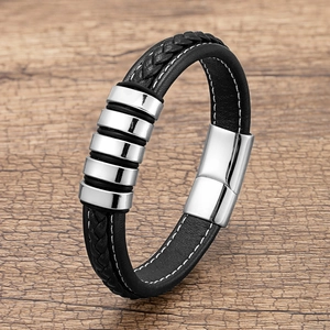 Braided black leather bracelet with silver metal stripes and magnetic clasp on wood