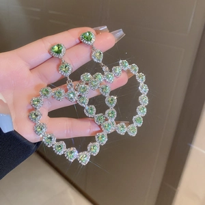 Exaggerated silver hollow heart earrings with sparkling rhinestones and green gems