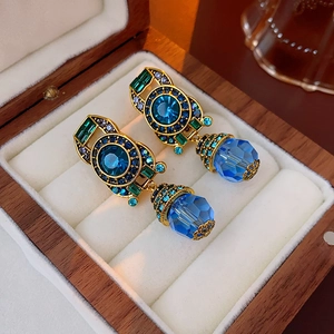 Close-up of vintage gold earrings with blue crystals in a luxury wooden jewelry box