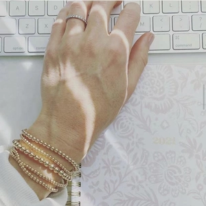 Detail of layered gold stainless steel beaded bracelets and pearl accent on hand