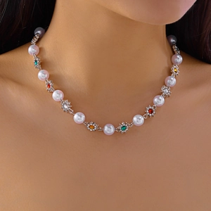 Close-up of pearl necklace with colorful gemstone flowers worn on a model neckline