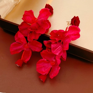Gros plan de boucles d'oreilles fleurs en tissu rouge avec crochets dorés élégants