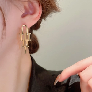 Close-up of gold irregular geometric drop earrings worn by a model for a modern look