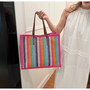 Close-up of rainbow crochet tote bag featuring brown faux leather handles and woven texture
