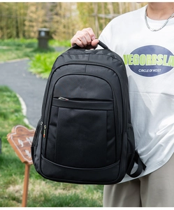 Close-up of a large capacity black business casual backpack held by a model in a park