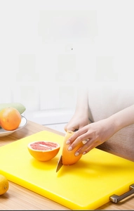 Thickened yellow PE cutting board with metal handle shown slicing a pomelo fruit