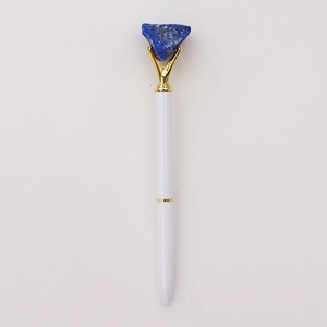 Detail van witte balpen met blauwe ruwe edelsteen in goudkleurige zetting