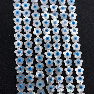 Witte bloemvormige schelpkraal met blauw oogpatroon op een zwarte achtergrond
