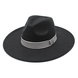Close-up of black wide-brim wool fedora hat with a stylish black and white striped band