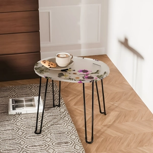 Detail of oval resin coffee table featuring purple floral patterns and black hairpin legs