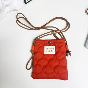 Detail of orange quilted nylon crossbody bag with rope strap and woven label