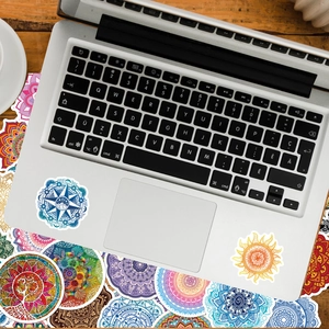 Mandala stickers with bohemian patterns applied to a silver laptop on a wooden desk