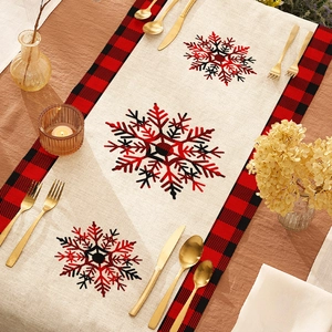 Christmas table runner with red black plaid border and snowflakes on wooden table
