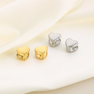 Titanium steel heart-shaped hoop earrings in gold and silver finishes on silk fabric