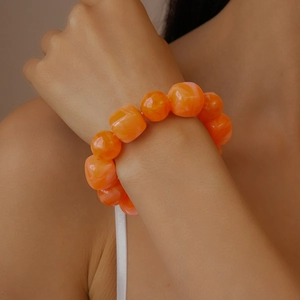 Close-up of bright orange acrylic beaded bracelet with irregular square resin charms