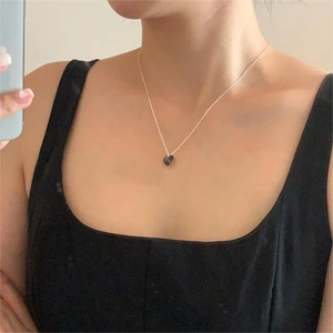 Detailed close-up of a 925 silver necklace with dark crystal heart pendant on clavicle