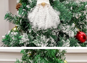 Close-up of a Christmas gnome hanging on a snowy tree branch with festive ornaments