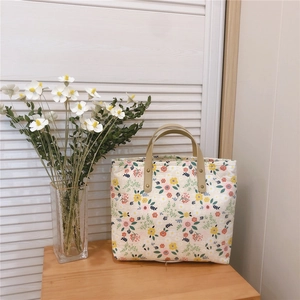 Close-up of floral canvas tote bag with yellow leather handles and rivet details