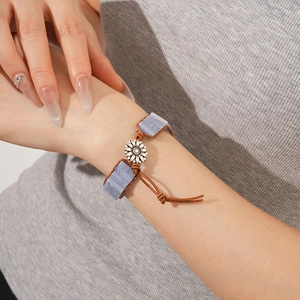Dettaglio del bracciale in pelle intrecciata con pietra blu e ciondolo a girasole
