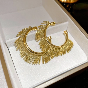 Detailed close-up of gold geometric C-shaped earrings with long metallic tassel fringe