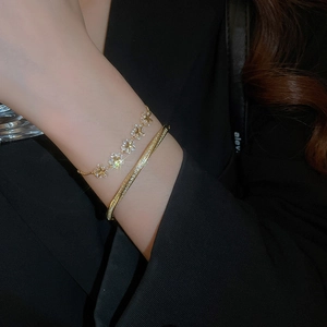 Close-up of gold plated star flower bracelet and rhinestone bangle on wrist