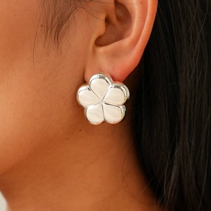 Close-up of polished silver flower stud earrings with a glossy metallic mirror finish
