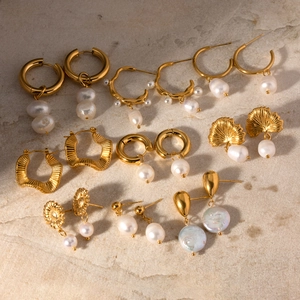 Golden stainless steel earring collection with freshwater pearls on gray stone