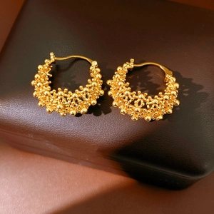 Vue détaillée de boucles d'oreilles circulaires plaquées or 18 carats au design granulaire