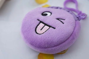 Close-up of purple plush coin purse with embroidered winking emoji and soft texture