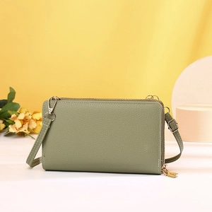 Close-up of green crossbody phone bag with litchi grain texture and dual gold zippers
