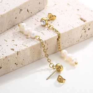 Gros plan de boucles d'oreilles vintage avec perles et dorure 18 carats sur pierre grise