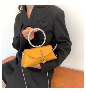 Close-up of yellow shoulder bag with rhinestone ring handle and V-shaped charm detail