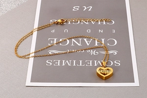 Detailed close-up of golden heart-shaped necklace with mom engraving on a decorative card