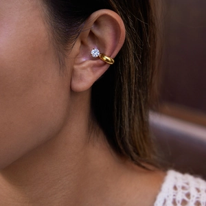 Elegant gold-plated ear cuff with a sparkling round-cut zircon on a model's ear