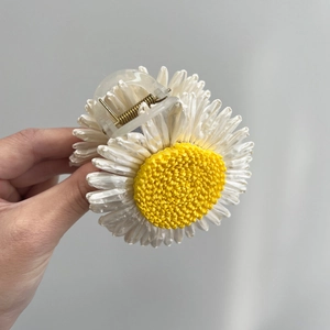Detailed view of daisy-shaped hair clip with white petals and yellow textured center