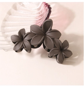 Detail of matte dark grey shark clip featuring three layered five-petal flowers