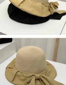 Detailed view of straw sun hat featuring a wide fabric brim and large bow decoration