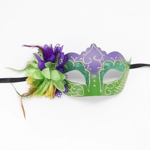 Detail of purple and green masquerade mask with glitter patterns and feathers