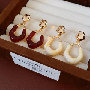 Close-up of red and cream oval resin earrings in a premium brown velvet jewelry box