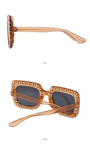 Detail view of square sunglasses featuring golden glitter amber frames and side structures