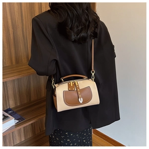 Détail d'un sac à main bicolore beige et marron avec finitions en cuir et boucles d'or