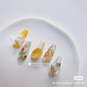 Macro detail of 5D floral nail art charms with relief tulip and butterfly designs