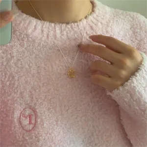 Close-up of minimalist gold heart pendant on silver chain necklace worn with pink sweater